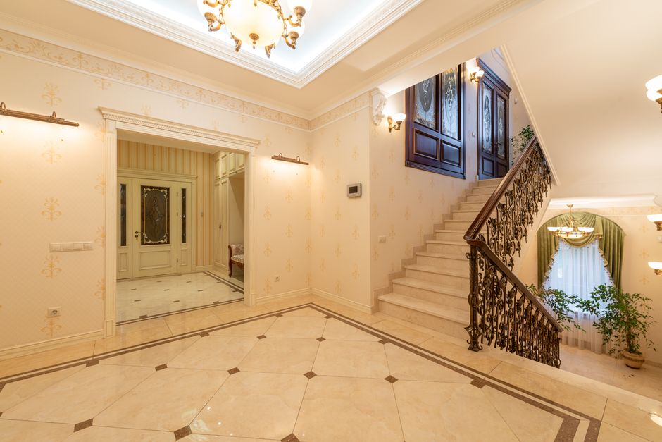 Spacious, well-lit interior featuring a grand staircase and elegant chandelier