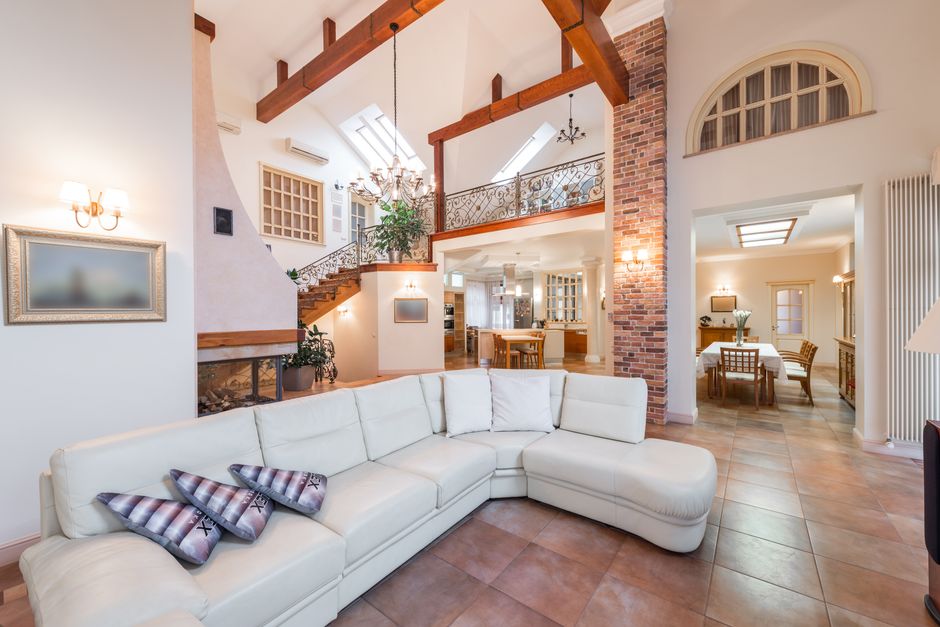Interior of spacious living room with sofa near kitchen with chairs and table next to stairs